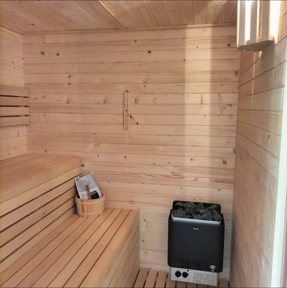 De sauna met houten banken en saunaoven